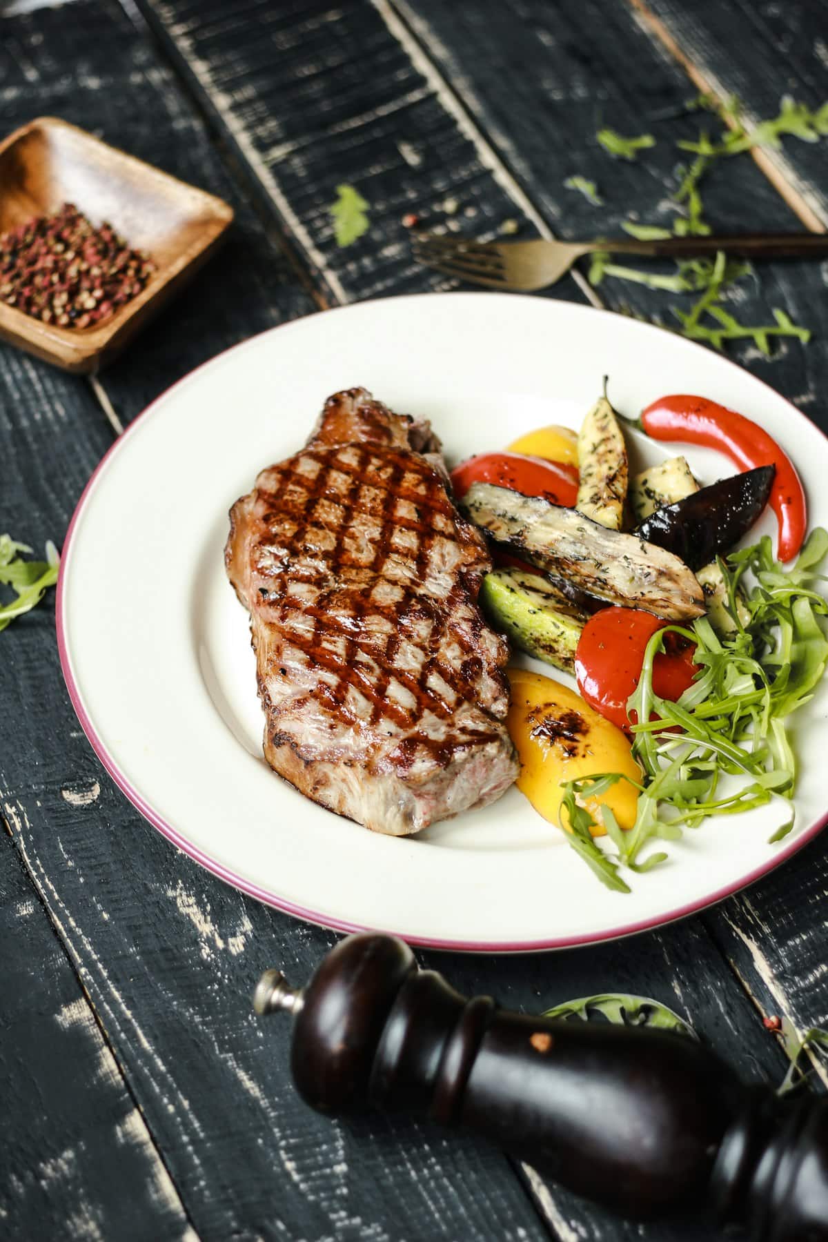 A grilled beef sirloin steak with char marks, served with vegetables