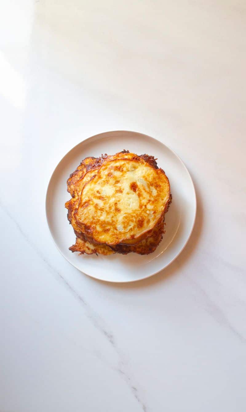 A golden pan-fried potato pancake on a white plate
