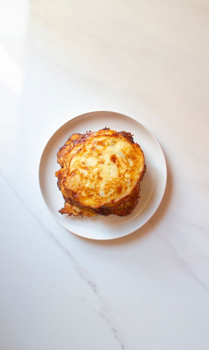 A golden pan-fried potato pancake on a white plate