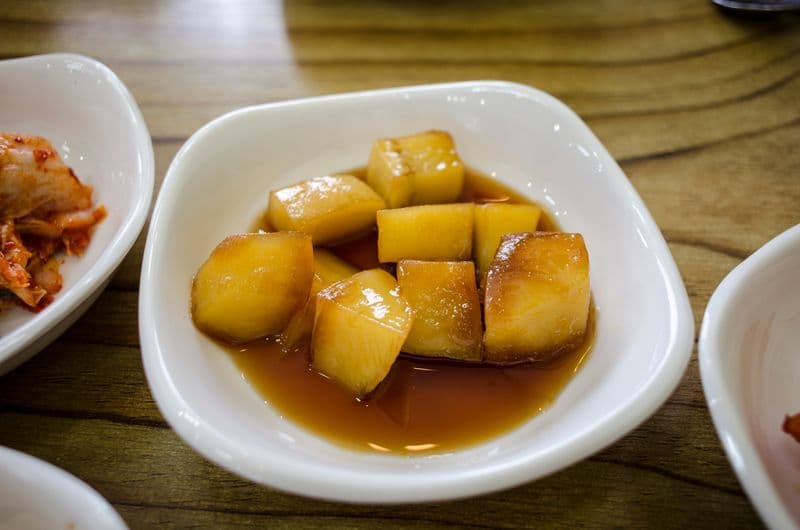 Glossy soy-braised potato cubes in a small white dish