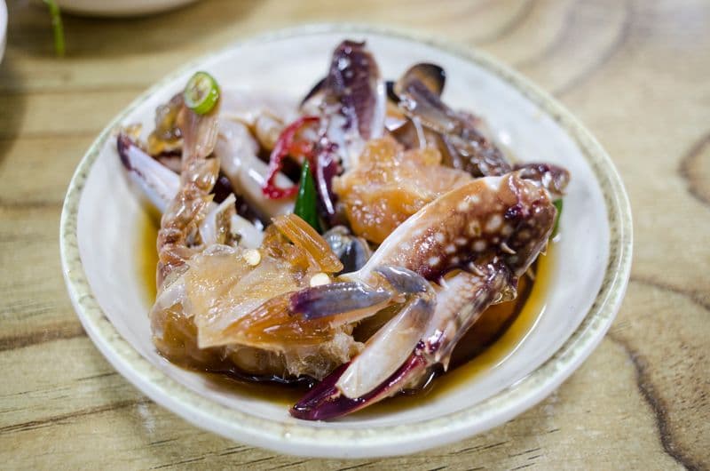 Raw crab pieces marinated in dark glossy soy sauce with chili and garlic