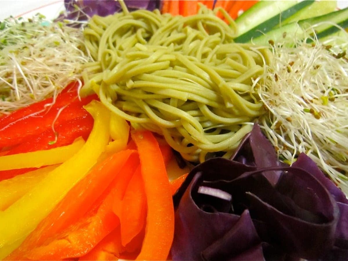 Buckwheat noodles surrounded by brightly coloured raw vegetables on a wide platter