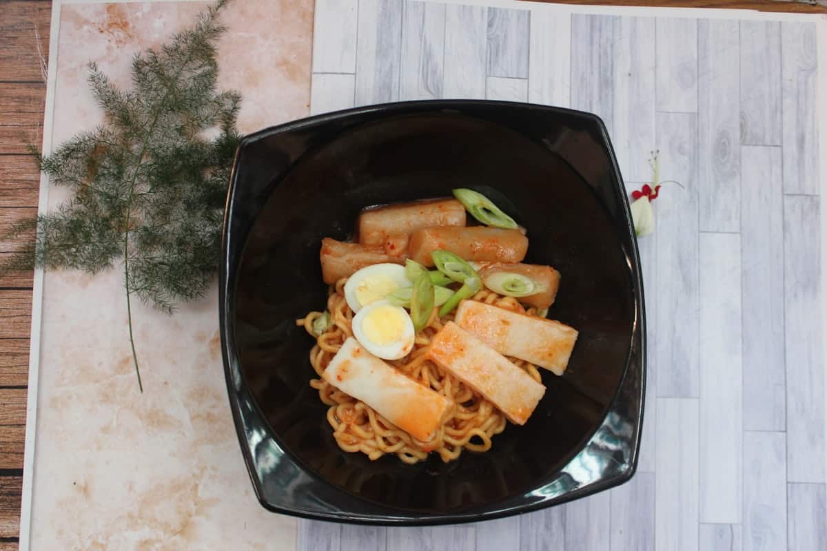 Chewy noodles tossed in spicy red sauce with rice cake and egg