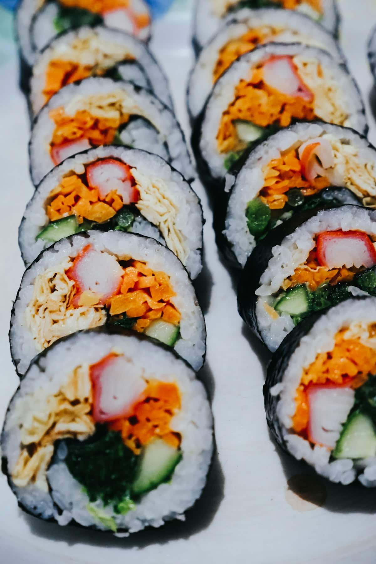 Sliced kimbap rolls showing rice, egg, carrot, and cucumber filling