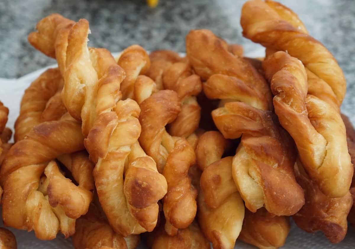 Golden twisted fried donuts stacked on a tray