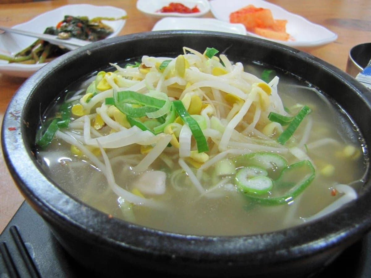 Bean sprout soup with rice and green onion in a dark stone bowl