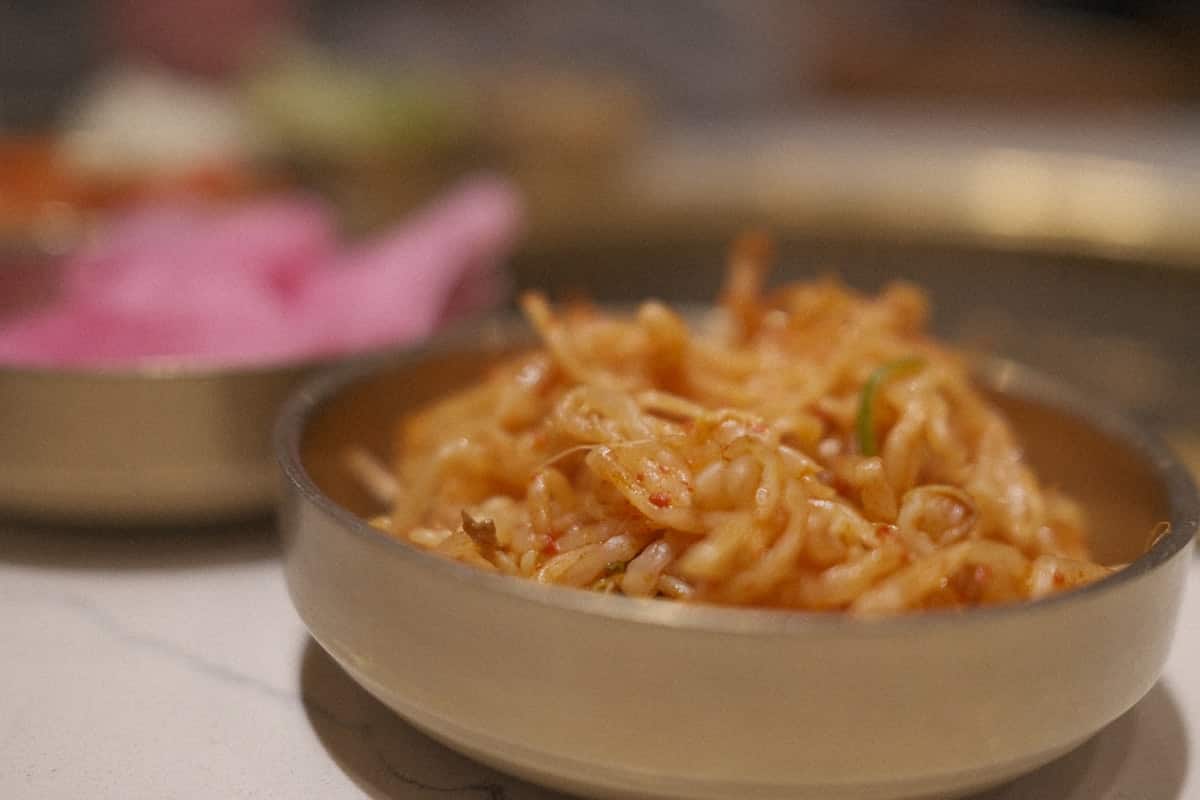 Seasoned bean sprouts in a bowl, lightly coated in sesame and chili