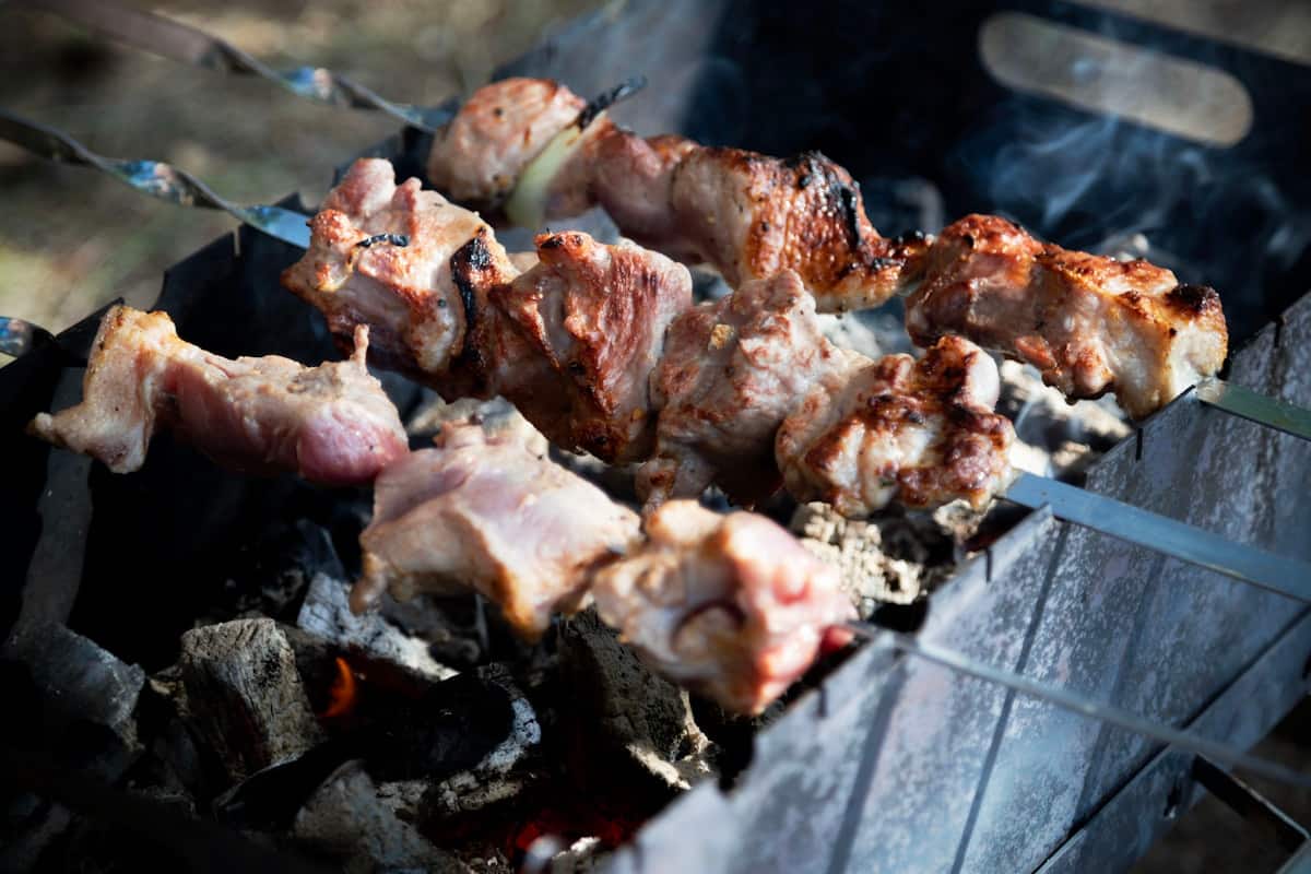Skewered marinated pork grilling over glowing charcoal