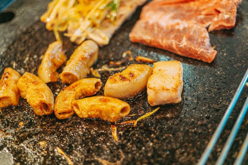 Grilled beef intestine pieces with char marks on a Korean BBQ grill plate