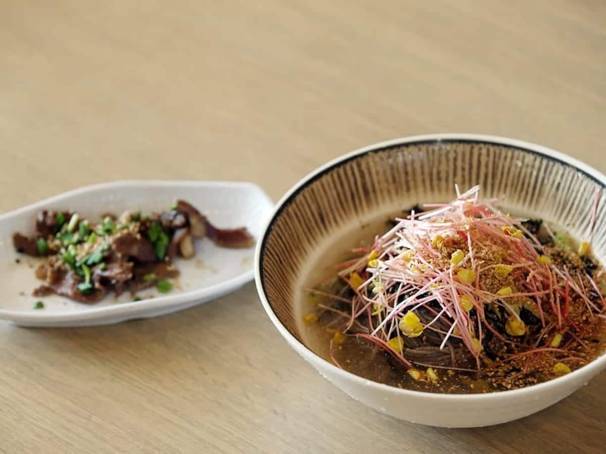 Buckwheat noodles topped with vegetables and sesame in a wide bowl