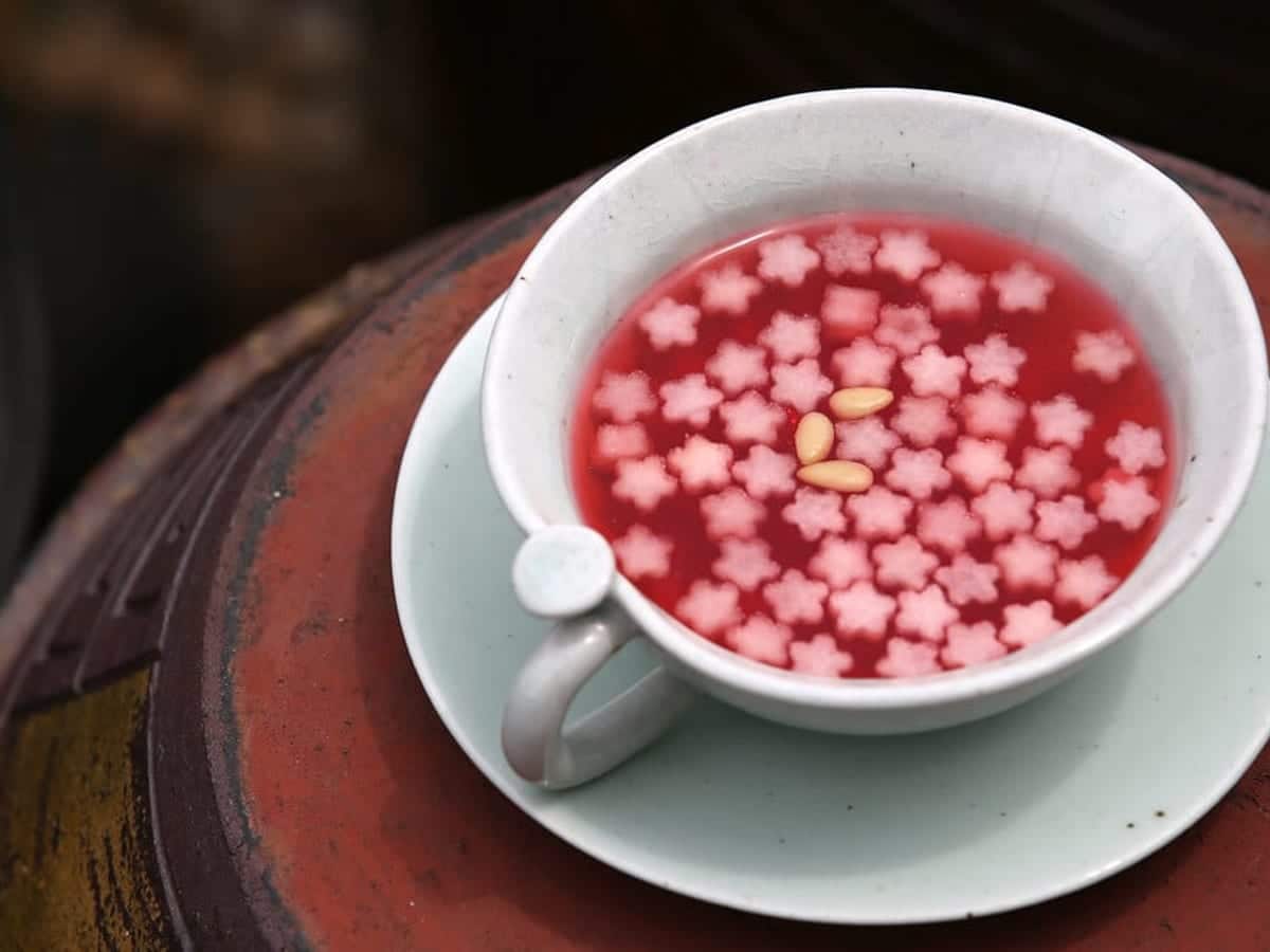 Deep pink berry punch in a white bowl with flower-shaped fruit garnish floating on top