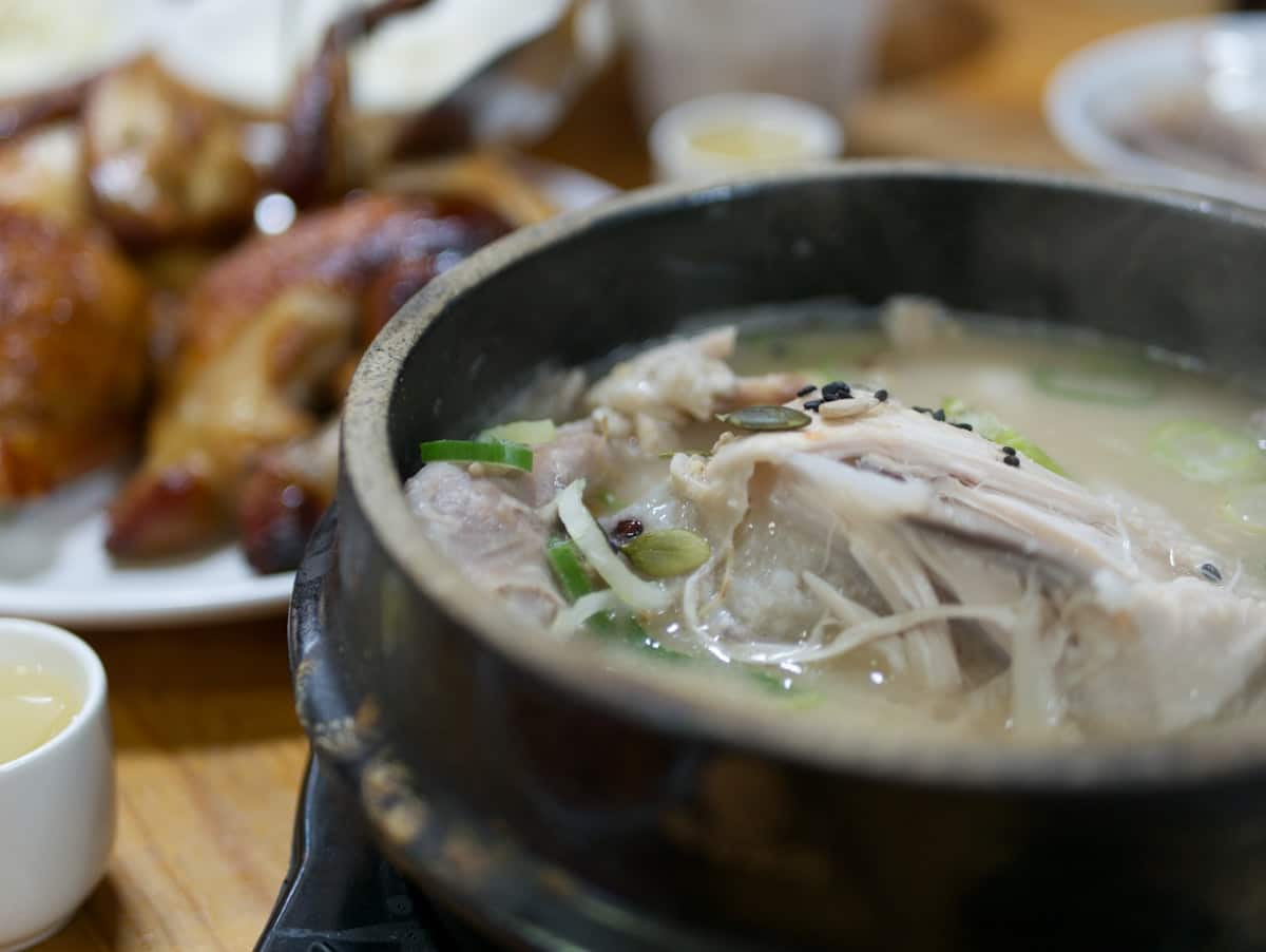 Whole small chicken in a milky ginseng broth with visible garlic and jujube