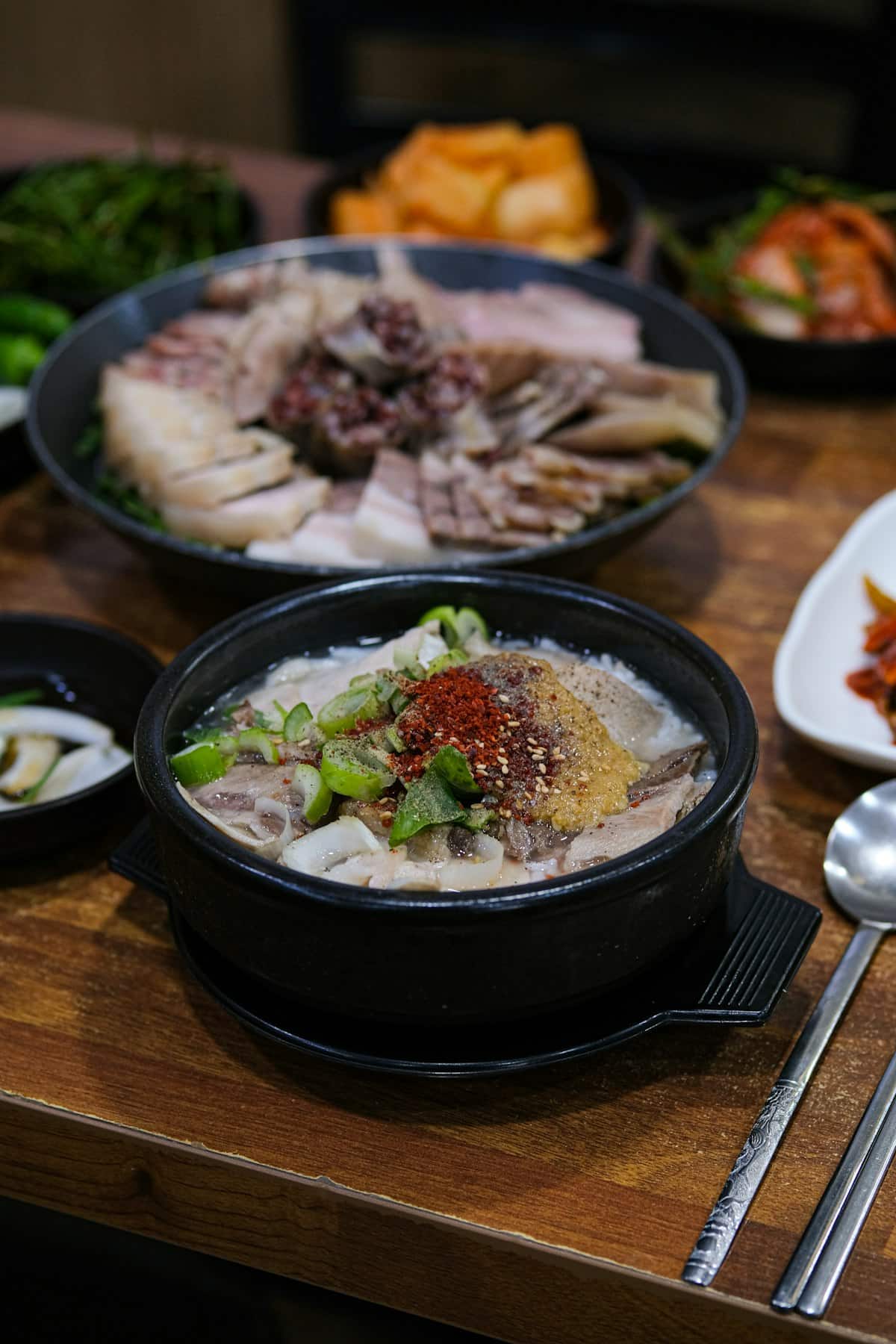 A bowl of milky white ox bone soup with sliced beef and green onion