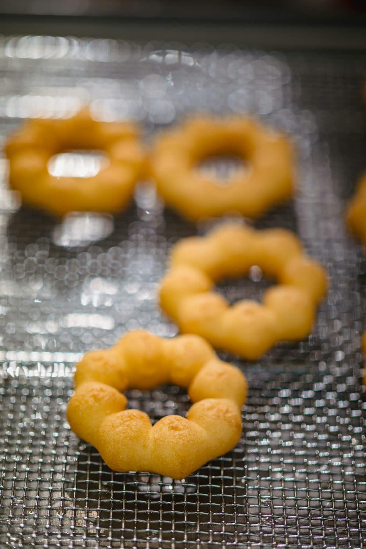 Small flower-shaped fried pastries cooling on a rack