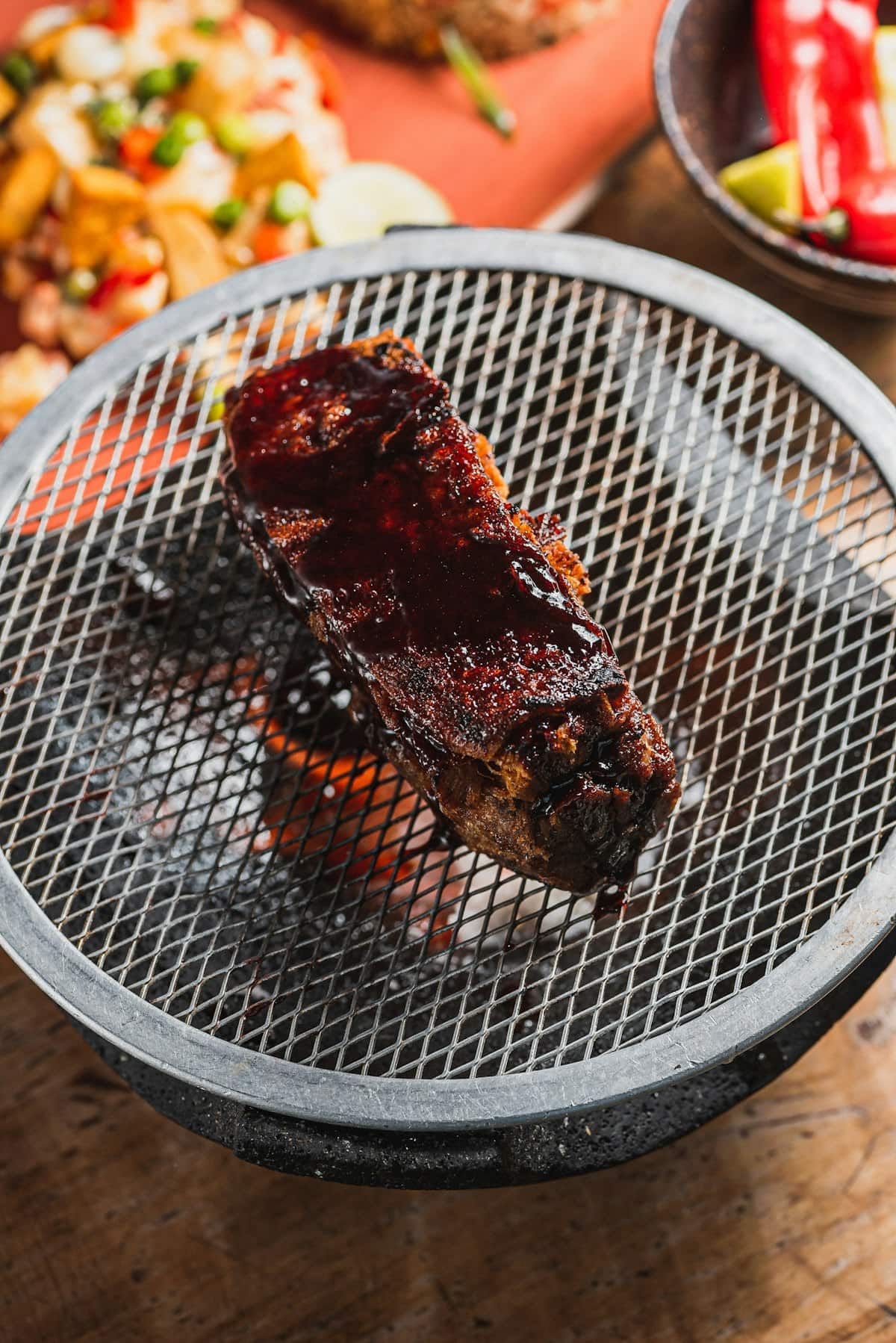 Marinated short ribs grilling over hot coals with glossy glaze